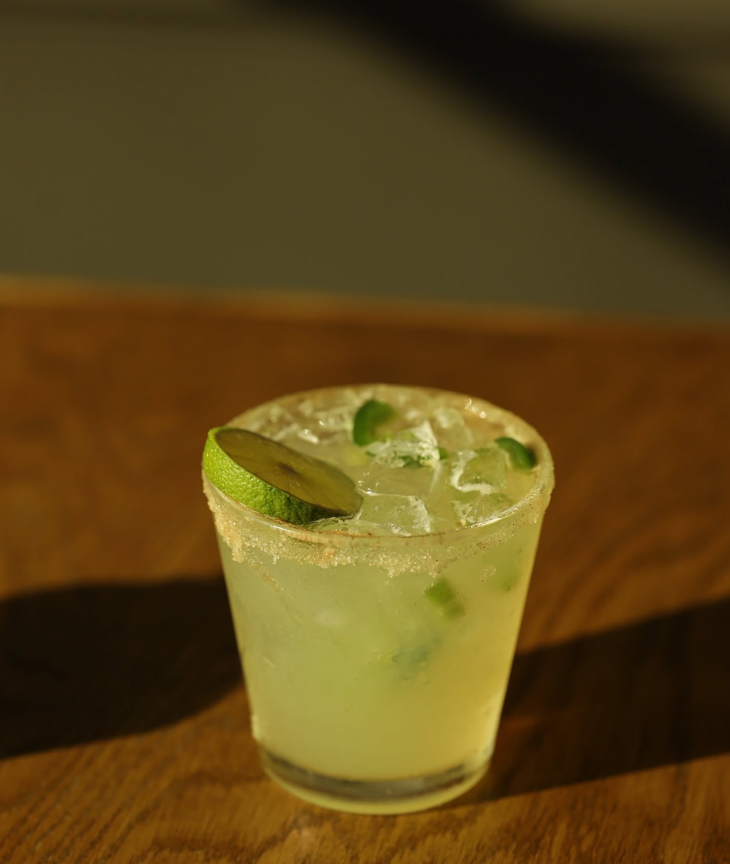 A salt-rimmed jalapeño margarita with a lime wheel.