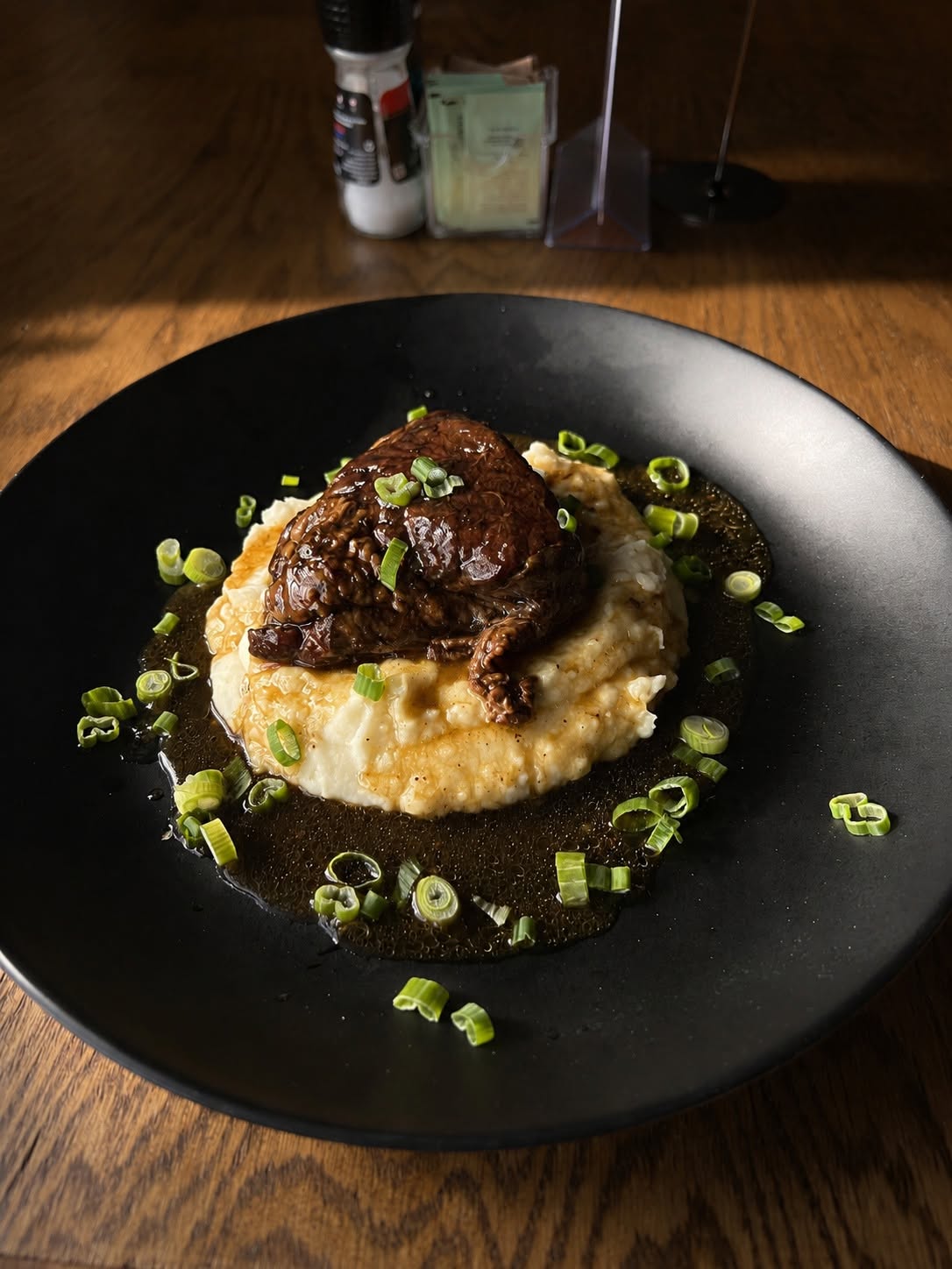 Braised short rib over cheddar grits with gravy and spring onion.