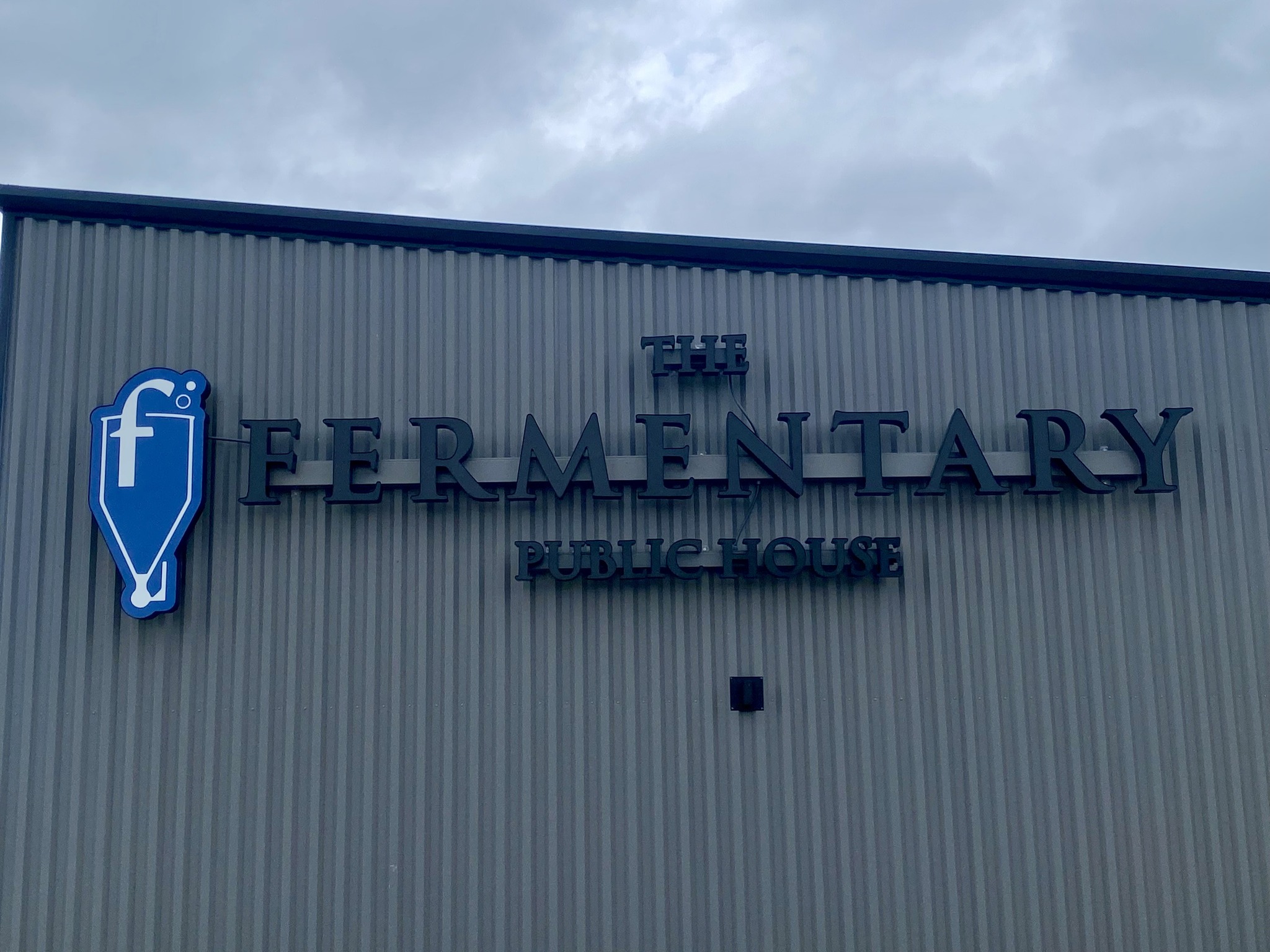 The Fermentary Public House lettering and the blue fermenter sign on the corrugated building.