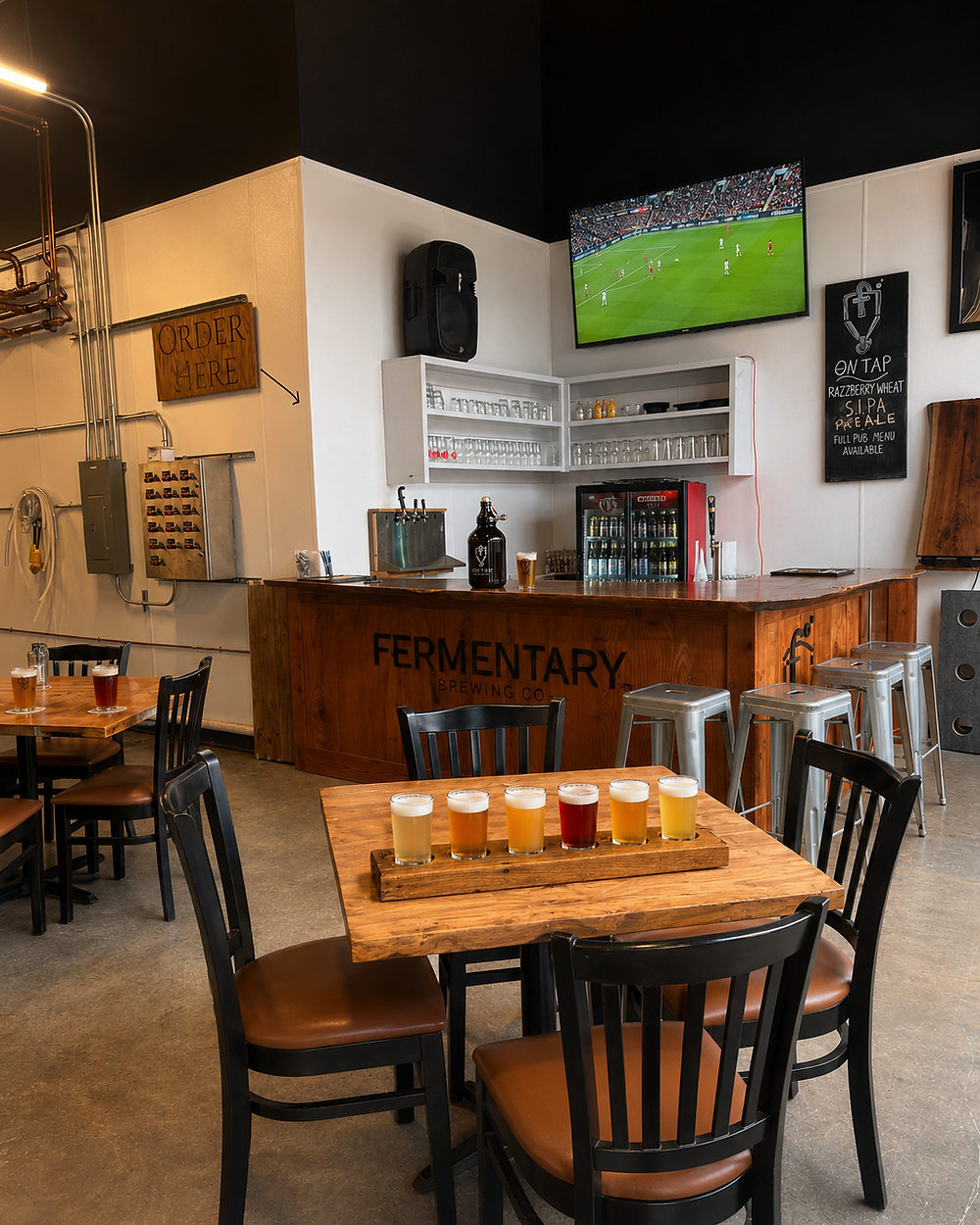 The brewery interior: a wooden bar carrying the Fermentary name, a tap tower, glassware and stools.
